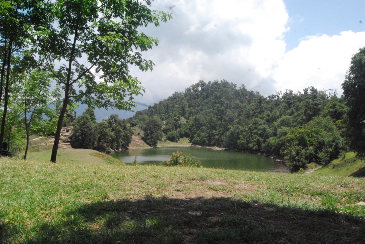 Deoriatal in the middle with dense forest of pine trees on hill and grey clouds covering the blue sky over head