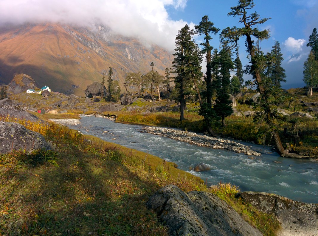 Supin river flowing calmly through the valley of god under the cloudy sky with beautiful pine trees on side