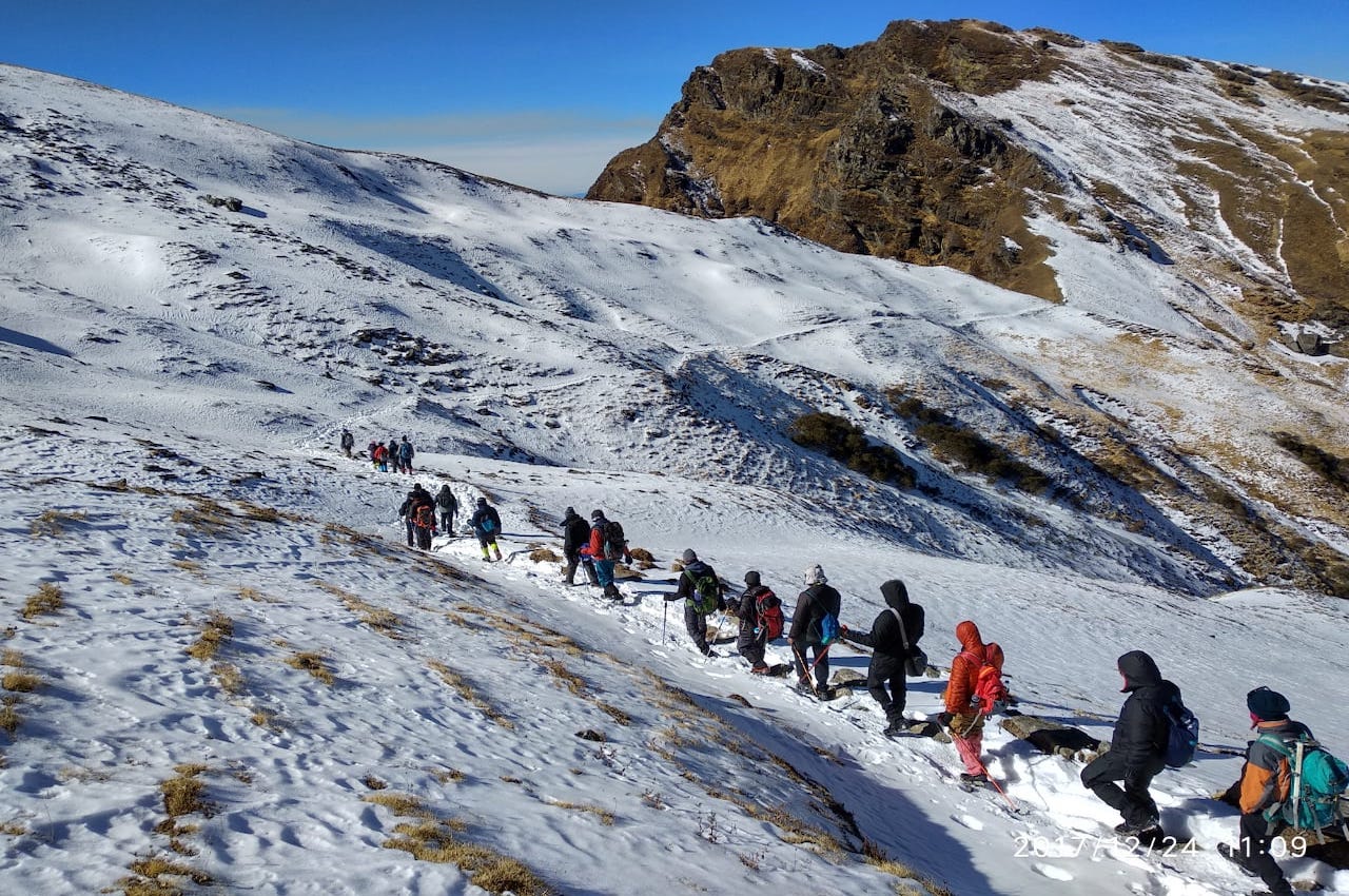 trekkers walking over snow covered ground at kuari pass trek