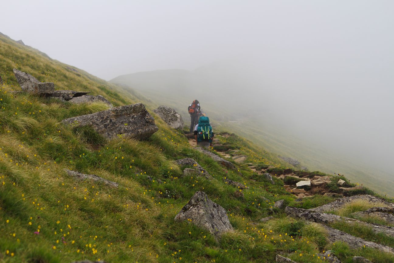 trekkers carrying their racksack walking through the fog enroute roopkund trek